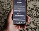 Une main tenant un smartphone sur lequel l'interface de ChatGPT est ouverte