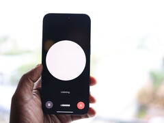 Une main tenant un smartphone dont l'écran affiche l'interface d'un assistant vocal