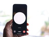 Une main tenant un smartphone dont l'écran affiche l'interface d'un assistant vocal