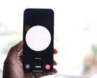 Une main tenant un smartphone dont l'écran affiche l'interface d'un assistant vocal
