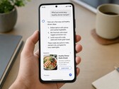 Une main tenant un smartphone affichant une réponse générée par l'IA, avec une publicité sponsorisée en dessous