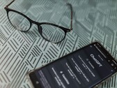 Un smartphone sur lequel l'application ChatGPT est ouverte, posé à côté d'une paire de lunettes sur une surface à motifs