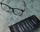 Un smartphone sur lequel l'application ChatGPT est ouverte, posé à côté d'une paire de lunettes sur une surface à motifs