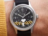 Gros plan sur le cadran noir de la Timex MK1 représentant Snoopy sur un fond à carreaux jaunes et noirs, avec des index arabes et des aiguilles luminescentes.