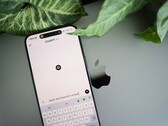 Un smartphone sur lequel est ouverte l'application ChatGPT, posé sur un ordinateur portable à côté de feuilles de plante