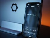 Un smartphone affiche l'interface de ChatGPT avec la question « En quoi puis-je vous aider ? »