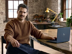 Henry Cavill assis à un bureau, un Googlebook à portée de main