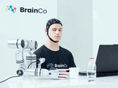 Un utilisateur de la technologie de contrôle mental de BrainCo saisissant mécaniquement une pomme par la seule force de la pensée.