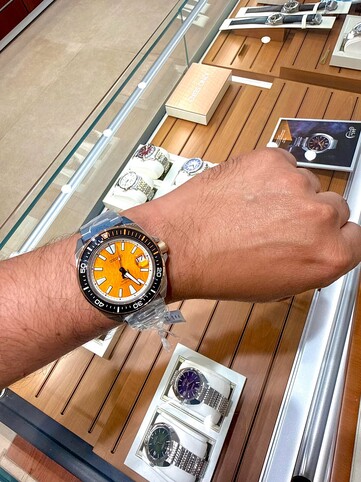 La montre de plongée Seiko Prospex HBB005K1, inspirée du tigre, portée au poignet, présente un cadran texturé de couleur ambre, une lunette noire rehaussée de touches orange, ainsi qu’un boîtier et un bracelet en acier inoxydable.