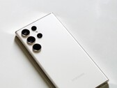 Smartphone Samsung Galaxy blanc doté de quatre caméras arrière, posé sur une surface claire.