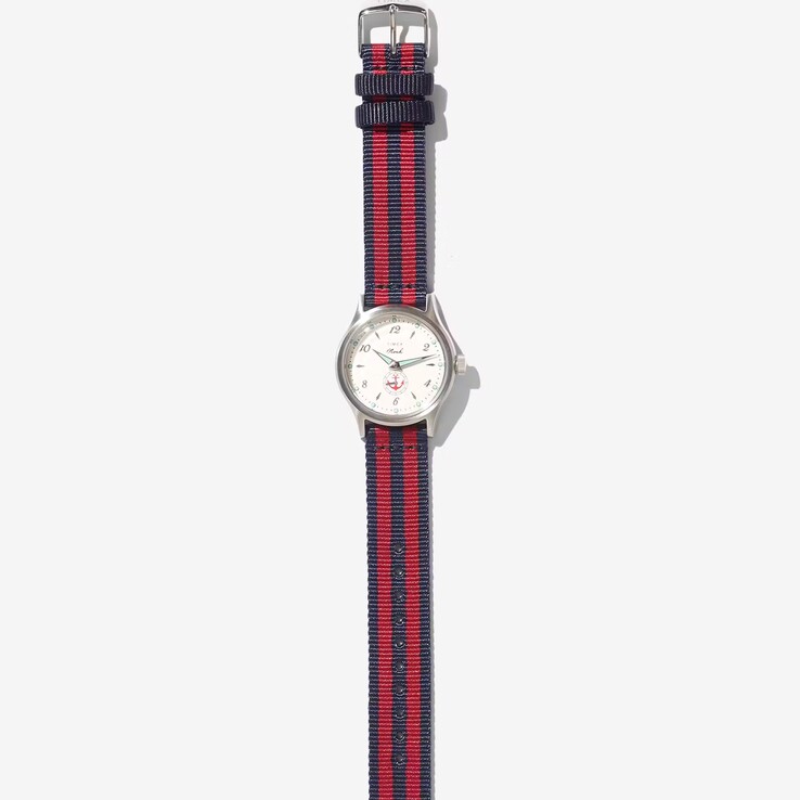 Montre Noah x Timex MK1 Anchor dotée d’un boîtier argenté de 36 mm, d’un cadran crème, d’un motif d’ancre et d’un bracelet en tissu rayé bleu marine et rouge.