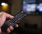 Main tenant une télécommande avec un téléviseur flou en arrière-plan