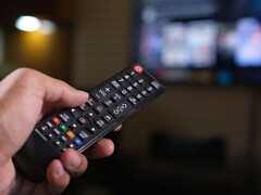 Main tenant une télécommande avec un téléviseur flou en arrière-plan