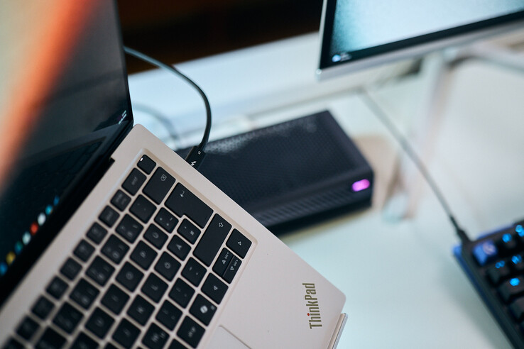 Gros plan sur un câble Thunderbolt 5 branché sur le port latéral d'un ordinateur portable Lenovo ThinkPad X9, avec l'eGPU Aorus en arrière-plan.