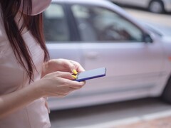 Une femme tapant sur son smartphone avec une voiture argentée en arrière-plan