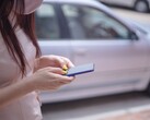 Une femme tapant sur son smartphone avec une voiture argentée en arrière-plan