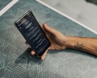 Main tenant un smartphone avec l’application ChatGPT ouverte au-dessus d’une table à motifs