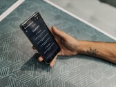 Main tenant un smartphone avec l’application ChatGPT ouverte au-dessus d’une table à motifs