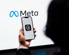 Une main tient un smartphone devant un grand logo Meta