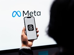 Une main tient un smartphone devant un grand logo Meta