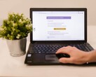 Un ordinateur portable posé sur un bureau, affichant une boîte de réception ouverte, avec une plante en pot à côté.