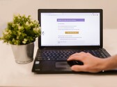 Un ordinateur portable posé sur un bureau, affichant une boîte de réception ouverte, avec une plante en pot à côté.