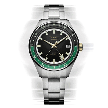 Timex Atelier GMT Première M1a avec un cadran noir, un anneau GMT vert et un bracelet en acier inoxydable.