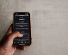 Main tenant un smartphone affichant l’interface de ChatGPT au-dessus d’une surface en pierre grise