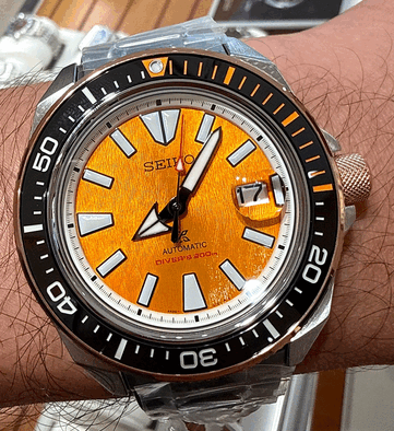 Gros plan sur la Seiko Prospex HBB005K1 mettant en valeur son cadran ambré texturé, ses index lumineux surdimensionnés, ses larges aiguilles, son guichet de date et sa lunette de plongée noire avec des repères orange.
