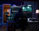 Un chercheur cagoulé travaille sur plusieurs écrans dans une installation sombre. Photo d'un pirate générique.