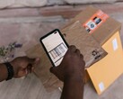 Une main tient un smartphone au-dessus d’un colis et scanne son code-barres.