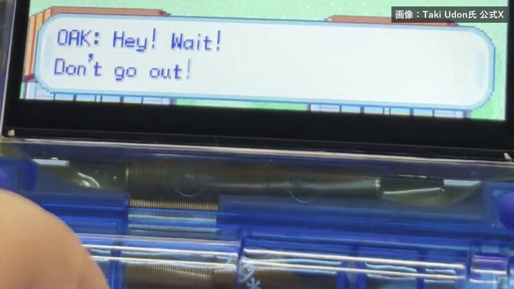 Gros plan de la console portable FPGBA SP bleu transparent, montrant sa charnière pliable et un dialogue Pokémon à l’écran.