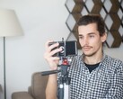 Un jeune homme se filme chez lui à l'aide d'un smartphone fixé sur un trépied