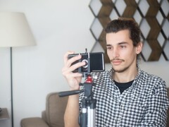 Un jeune homme se filme chez lui à l'aide d'un smartphone fixé sur un trépied