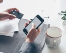 Personne tapotant sur un smartphone tout en tenant une carte bancaire dans l'autre main