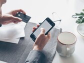 Personne tapotant sur un smartphone tout en tenant une carte bancaire dans l'autre main