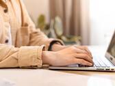 Des mains tapant sur le clavier d'un ordinateur portable ouvert, posé sur un bureau bien éclairé