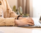Des mains tapant sur le clavier d'un ordinateur portable ouvert, posé sur un bureau bien éclairé