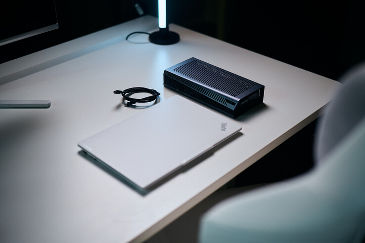 Un ordinateur portable ThinkPad blanc fermé posé à côté de l'eGPU compact Aorus RTX 5060 Ti AI Box et d'un câble Thunderbolt spiralé sur un bureau.
