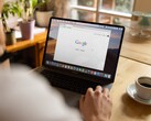 Une personne devant un ordinateur portable, avec la page d’accueil de Google ouverte, à côté d’une tasse de café