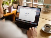 Une personne devant un ordinateur portable, avec la page d’accueil de Google ouverte, à côté d’une tasse de café