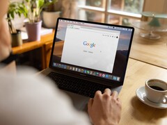 Une personne devant un ordinateur portable, avec la page d’accueil de Google ouverte, à côté d’une tasse de café