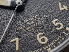 Gros plan sur le cadran noir texturé de la Timex Expedition Field Post Titanium, doté de chiffres arabes, d’aiguilles et d’index luminescents, ainsi que d’un guichet de date.