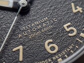 Gros plan sur le cadran noir texturé de la Timex Expedition Field Post Titanium, doté de chiffres arabes, d’aiguilles et d’index luminescents, ainsi que d’un guichet de date.