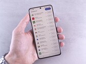 Une main tient un smartphone sur lequel s'affiche une liste de mises à jour.