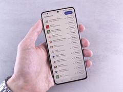 Une main tient un smartphone sur lequel s'affiche une liste de mises à jour.