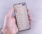 Une main tient un smartphone sur lequel s'affiche une liste de mises à jour.