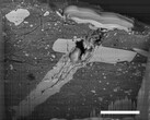 Image au microscope électronique à balayage d'un cratère d'impact de micrométéorite dans une particule de matériau de l'astéroïde Bennu (Source de l'image : NASA, et Zia Rahman)