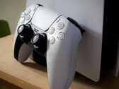 Une photo d’une manette DualSense PlayStation 5 appuyée contre une console PS5