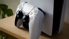 Une photo d’une manette DualSense PlayStation 5 appuyée contre une console PS5